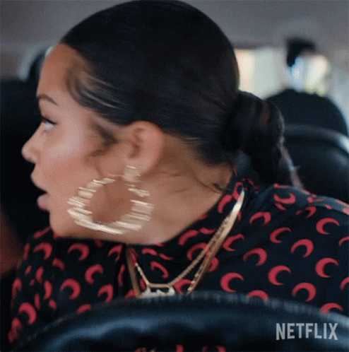 A Woman Wearing Hoop Earrings Is Sitting In A Car With Netflix Written On The Bottom Of The Screen GIF
