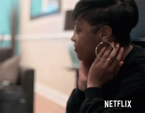 A Woman Wearing Hoop Earrings Is Sitting In Front Of A Netflix Screen . GIF