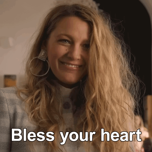 A Woman Wearing Hoop Earrings Smiles With The Words Bless Your Heart Above Her GIF