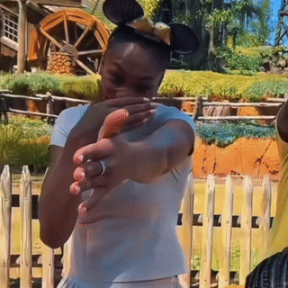 A Woman Wearing Mickey Mouse Ears Covering Her Face GIF