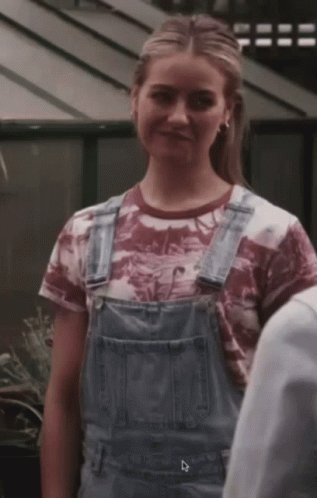 A Woman Wearing Overalls And A T-Shirt With The Letter D On The Bottom Right GIF