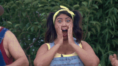 A Woman Wearing Overalls And A Yellow Headband Is Making A Surprised Face While Standing Next To A Man . GIF