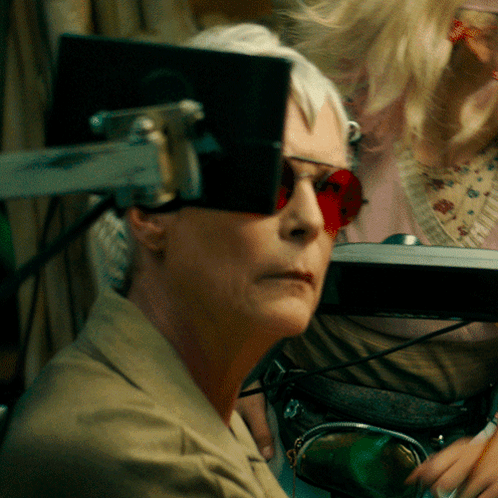 A Woman Wearing Red Sunglasses Is Looking At A Monitor GIF