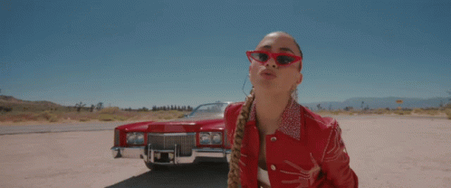 A Woman Wearing Red Sunglasses Stands In Front Of A Red Cadillac GIF