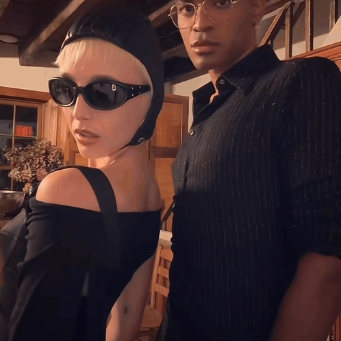 A Woman Wearing Sunglasses And A Helmet Stands Next To A Man GIF