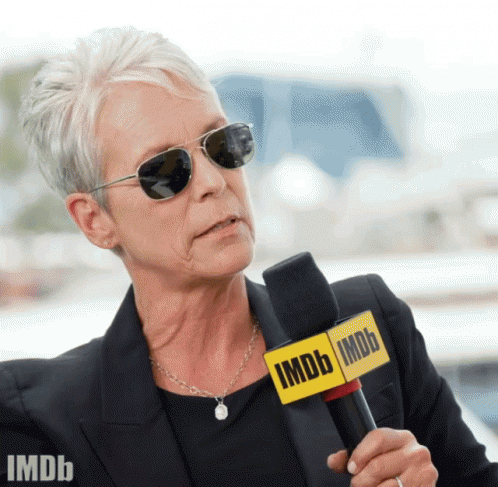 A Woman Wearing Sunglasses And A Microphone That Says Imdb On It GIF