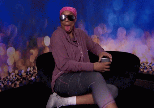 A Woman Wearing Sunglasses And A Pink Headband Sitting On A Couch GIF