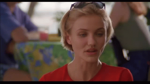 A Woman Wearing Sunglasses And A Red Shirt Is Looking At The Camera GIF