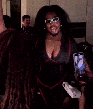 A Woman Wearing Sunglasses And A Robe Is Taking A Selfie GIF