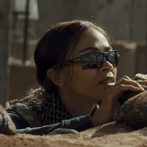 A Woman Wearing Sunglasses And A Scarf Laying On The Ground GIF