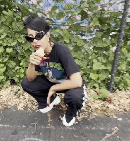 A Woman Wearing Sunglasses And A Shirt That Says I 'M Black Is Eating A Banana GIF