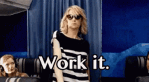 A Woman Wearing Sunglasses And A Striped Shirt Is Standing In Front Of A Blue Curtain And Says Work It . GIF
