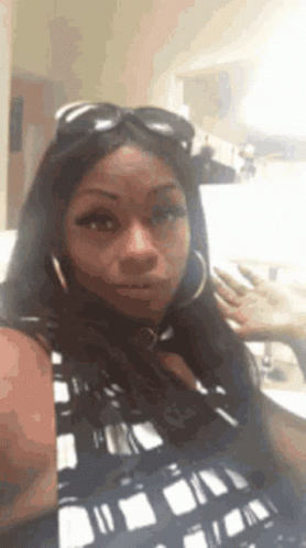 a woman wearing sunglasses and hoop earrings is taking a selfie