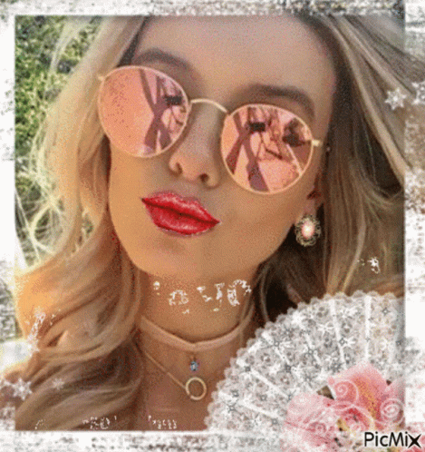 A Woman Wearing Sunglasses And Red Lipstick Is Surrounded By Flowers GIF