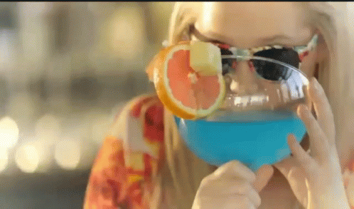 A Woman Wearing Sunglasses Drinking A Blue Drink GIF