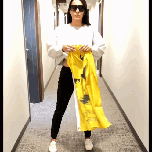 A Woman Wearing Sunglasses Holds Up A Yellow Flag That Says ' On A Sunny Day ' On It GIF