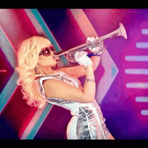 A Woman Wearing Sunglasses Is Blowing A Trumpet In Front Of A Purple Background GIF