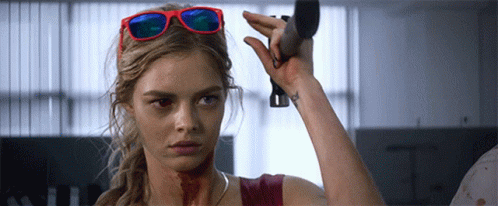 A Woman Wearing Sunglasses Is Holding A Knife GIF