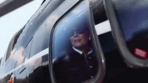 A Woman Wearing Sunglasses Is Looking Out Of A Helicopter Window . GIF