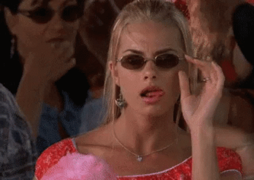 A Woman Wearing Sunglasses Is Making A Funny Face While Holding Cotton Candy . GIF
