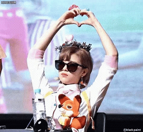 A Woman Wearing Sunglasses Is Making A Heart With Her Hands . GIF