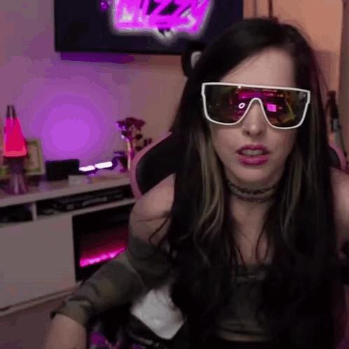 A Woman Wearing Sunglasses Is Sitting In A Chair In Front Of A Tv . GIF