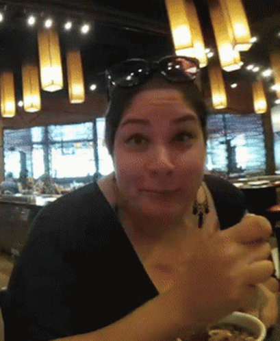 A Woman Wearing Sunglasses Is Sitting In A Restaurant GIF