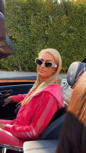 A Woman Wearing Sunglasses Is Sitting In The Back Seat Of A Car . GIF