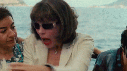 A Woman Wearing Sunglasses Is Sitting On A Boat With Other People GIF