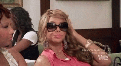 A Woman Wearing Sunglasses Is Sitting On A Couch . GIF