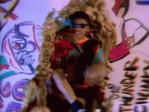 A Woman Wearing Sunglasses Is Standing In Front Of A Wall That Says Thunder GIF