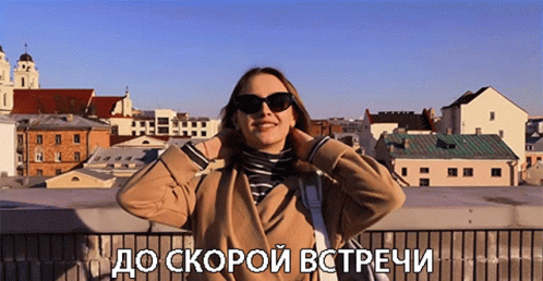 A Woman Wearing Sunglasses Stands In Front Of A City With The Words " До Скорой Встречи " Written Below Her GIF