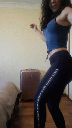A Woman Wearing Under Armour Pants Is Dancing In A Room GIF