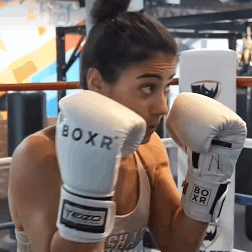 A Woman Wearing White Boxr Boxing Gloves In A Boxing Ring GIF