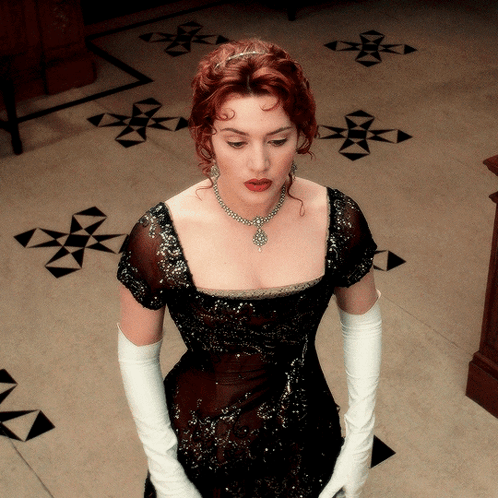 A Woman Wearing White Gloves And A Black Dress GIF