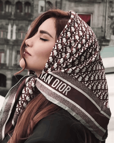 A Woman Wears A Scarf That Says Christian Dior On It GIF