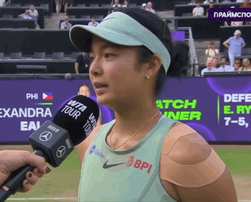 A Woman With A Bandage On Her Arm Is Being Interviewed By A Bpi Microphone GIF