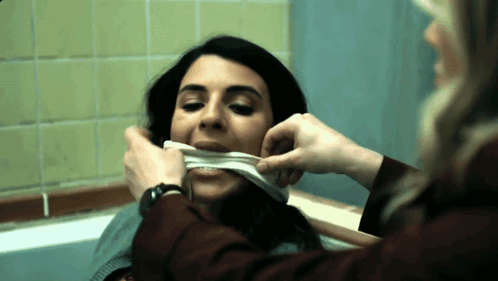 A Woman With A Bandage On Her Mouth Looks At Another Woman GIF
