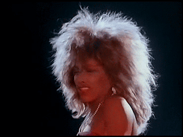 A Woman With A Big Afro Is Wearing A Red Dress And Pearls GIF
