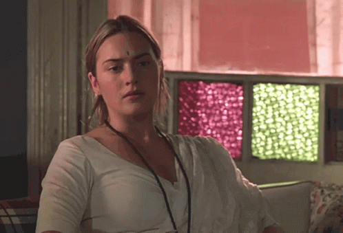 A Woman With A Bindi On Her Forehead Is Sitting In Front Of A Window GIF