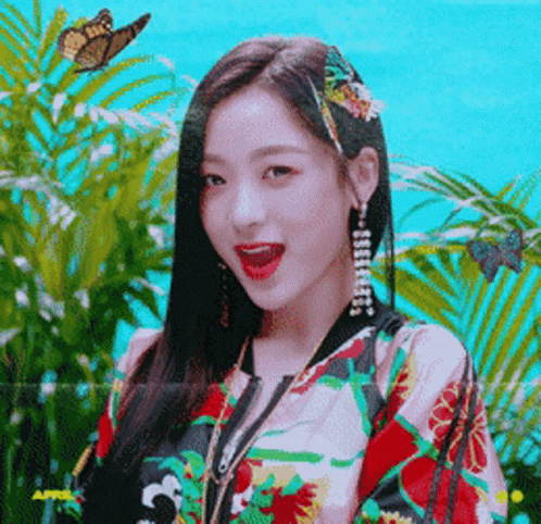 A Woman With A Butterfly In Her Hair Is Wearing A Jacket With Flowers On It GIF