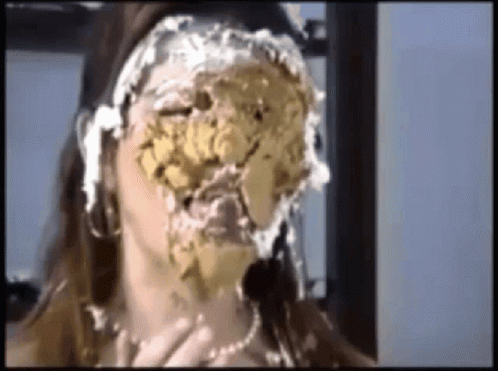 a woman with a cake on her face is sitting in front of a window .