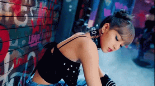 A Woman With A Choker Around Her Neck Is Sitting In Front Of A Wall With Graffiti On It . GIF