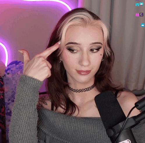 A Woman With A Choker Is Pointing To Her Forehead GIF
