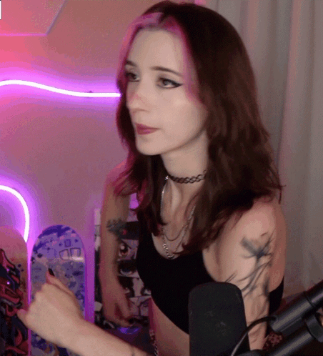 A Woman With A Choker On Her Neck Is Standing In Front Of A Microphone GIF