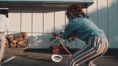 A Woman With A Cowboy Hat On The Ground In Front Of A Red Cooler GIF