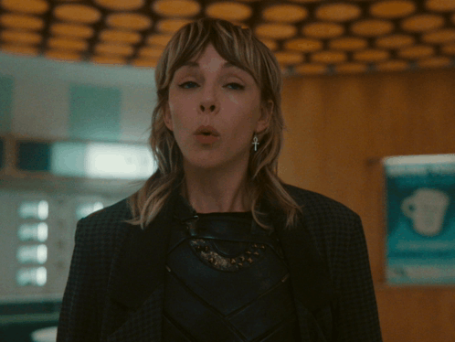 A Woman With A Cross On Her Ear Looks Surprised GIF