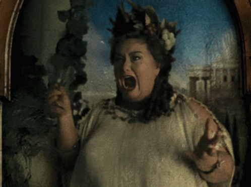 A Woman With A Crown Of Leaves On Her Head Holds A Glass GIF