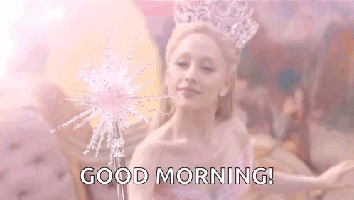 A Woman With A Crown On Her Head Is Holding A Wand And Saying `` Good Morning '' . GIF