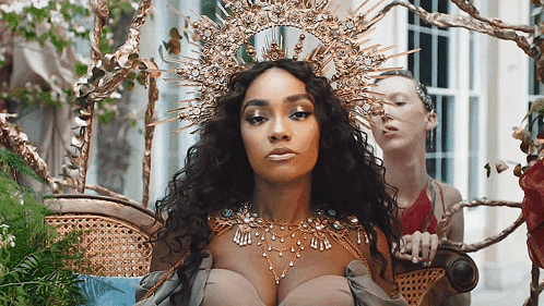 Woman With Crown Sitting In Chair With Another Woman GIF